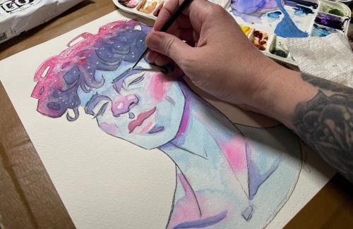close-up of artist painting a pastel-colored portrait of a peaceful person's face