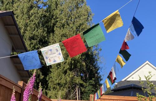 blue, white, red, green, and yellow flags offering words of gratitude, love, and creation move in a soft breeze