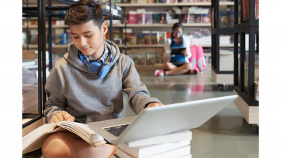 Kids reading and using laptops in library