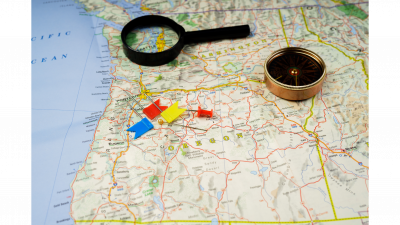 Map of Oregon with pins, magnifying glass and compass 