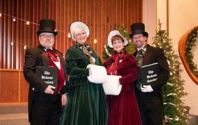 Four people dressed up in English caroling outfits