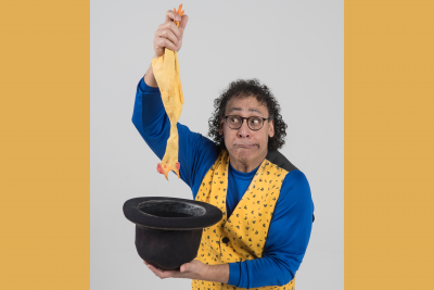 comedian Angel Ocasio pulling a rubber chicken out of black top hat